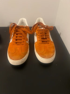 Valentino flycrew  - Säljer ett par Valentino flycrew i orange mocka med vita läderdetaljer och Valentinos ikoniska Rockstud-detaljer baktill. Använda men i bra skick. Mockan är fin med visst normalt slitage och lätt färgskiftning framtill. Inga hål eller sprickor. Sulorna har tydligt men normalt användningsslitage. Insidan är hel och ren. Se bilder för exakt skick. Storlek 41 men passar även 42 Låg modell, bekväma och stilrena. Snabb affär prioriteras sänks mycket vid snabb äffar fraktas inom 24 timmar 