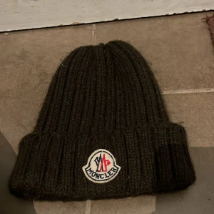 Brun ribbad mössa från Moncler - Snygg brun ribbad mössa från Moncler med broderad logotyp framtill. Perfekt för kyliga dagar med stil.