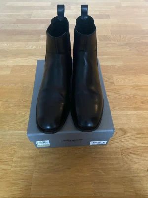 Vagabond boots - Säljer ett par stilrena svarta boots från Vagabond.Skorna är gjorda i slätt skinn och har elastiska paneler på sidorna för enkel påtagning. Perfekta för dig som gillar klassisk och enkel design.