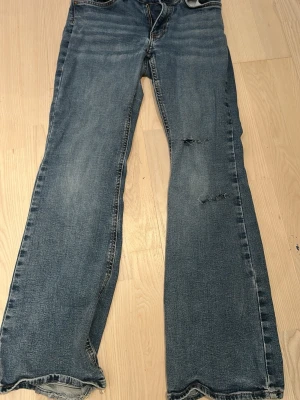Blå bootcut jeans med slitningar - Säljer ett par blå bootcut jeans med slitna detaljer och hål på ena benet. Hålen ör gjorda själv!💞🫶 Jensen är från Gina och är i st 36 lågmidjad