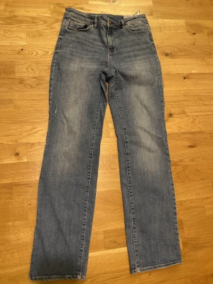 Vero Moda Blå raka jeans med klassisk look - Säljer ett par blå jeans med rak passform och klassisk femficksdesign. Jeansen har en snygg tvätt med lätt slitning och är tillverkade i jeansmaterial. De är precis samma modell som de mörkblåa! 