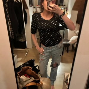 Svart prickig body med puffärm - Säljer en svart topp med vita prickar / polka dot och puffiga axlar. Toppen har rund halsringning och åtsittande passform med halvlånga ärmar. Perfekt för dig som gillar trendig stil och till fest 