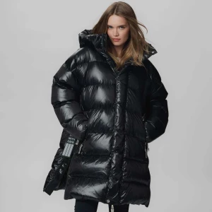 Svart pufferjacka från CAYA - Säljer en svart, lång och oversized pufferjacka från CAYA i dun och fjäder, köpt för 7500kr och använd endast en gång