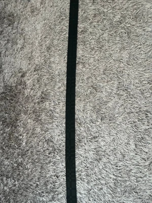 Burberry bälte med rutigt och svart - Säljer ett snyggt Burberry bälte med klassiskt rutigt mönster i beige, svart och rött på ena sidan och svart präglad yta på andra sidan. Bältet har ett guldigt metallspänne med 'B'-logga. Perfekt accessoar för att lyfta din outfit.