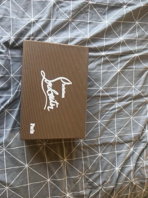 Marinblå sneakers från Louboutin - Säljer ett par marinblå sneakers från Louboutin i mocka med klassisk röd sula och broderad logga på hälen. Skorna har snörning och en stilren, rund tå. Perfekta för dig som vill ha något exklusivt och snyggt till vardagslooken.