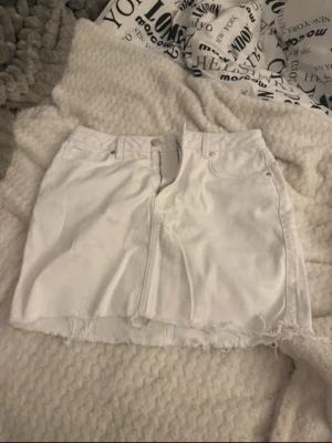 Vit jeanskjol från RGNC x nu-in - Säljer en vit jeanskjol från RGNC x nu-in med rå kant nertill och klassisk femficksdesign. Kjolen har dragkedja och knapp framtill samt bälteshällor. Storleken är mindre i storlek💞