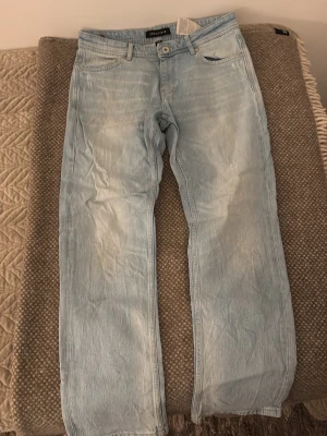 New Yorker Jeans - Säljer ett par ljusblå jeans från New Yorker med klassisk femficksdesign och raka ben. Jeansen har en snygg tvättad look och är tillverkade i mjukt bomullsmaterial. Passar dig som gillar en avslappnad och stilren vibe. Jeansen har passformen regular. Jeansen har används väldigt fåtal gånger och är i ny skick