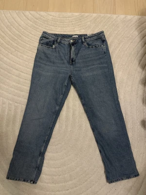 Blå jeans  - Säljer ett par klassiska blå jeans från Cubus  i storlek 36/32. Jeansen har rak passform, fem fickor och knappstängning framtill. Materialet är slitstark denim i bomull och färgen är en snygg mellanblå ton. Perfekt för dig som gillar enkel och tidlös stil.