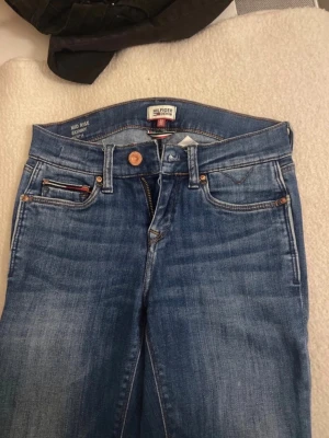 Tommy Hilfiger blå skinny jeans - Snygga blå skinny jeans från Tommy Hilfiger Denim med klassisk femficksdesign och midwaist. Jeansen har en fräsch tvättad look, kopparfärgade nitar och detaljerade sömmar. Materialet är jeans med en mjuk känsla och stretch för extra komfort.