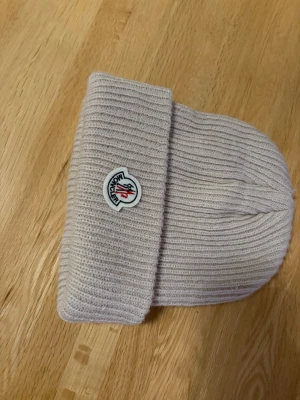 Moncler mössa - beige stickad mössa från Moncler med ribbad struktur. 