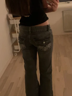 Snygga Grå bootcut jeans Gina Tricot 158 - Säljer ett par gråa bootcut jeans från Gina Tricot i storlek 158. Jeansen har snygga broderade detaljer på bakfickorna och klassisk femficksmodell. Materialet är jeans och passformen är normal med låg midja.