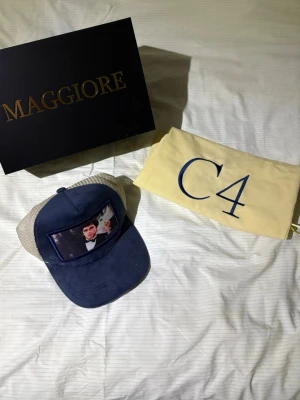 Blå och beige keps från Maggiore - Säljer en snygg truckerkeps från Maggiore i blått och beige med mesh på sidorna och baksidan. 