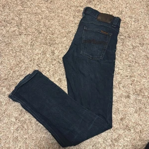 Mörkblå slim jeans från Nudie Jeans 30 / 32 - Snygga mörkblå jeans från Nudie Jeans med snygg tvätt och smal passform. Storleken är: W30 | L32. Mycket fint skick och fina jeans. Se mått på alla bilder. Tighta i modellen, mer som 28.