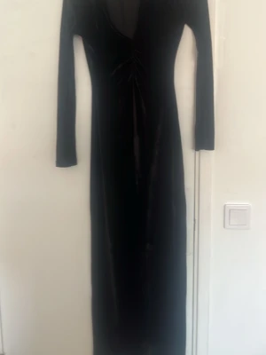Svart långärmad klänning Gina Tricot - Snygg svart långklänning från Gina Tricot i storlek XS. Klänningen har lång ärm, v-ringad hals och är figurnära med en cool rynkdetalj framtill. Materialet är mjukt och har en lätt glansig finish som ger en lyxig känsla.