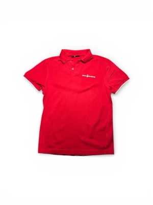 Röd piké Sail Racing S - Säljer en röd pikétröja från Sail Racing i storlek S. Tröjan har klassisk krage, korta ärmar och två röda knappar framtill. Materialet är mjuk bomull och loggan är broderad i vitt på bröstet. Perfekt för dig som gillar sportig och stilren look.