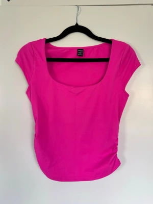 Rosa topp med rynkade sidor, storlek S - Säljer en starkt rosa topp med rynkade detaljer på sidorna i storlek S. Toppen har rundad, bred urringning och korta ärmar. - Köper du innan kl 16:00 kan jag posta samma dag! 🩷