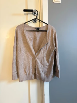 Beige kofta från H&M  - En enkel och stilren beige kofta från H&M  i storlek S. Koftan har medellång ärm och knappar framtill 