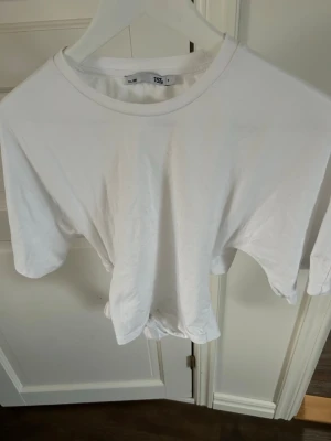 Vit t-shirt med knyte i ryggen - Säljer en enkel vit t-shirt från Lager 157 i storlek S. Har knyte i ryggen, endast använd en gång