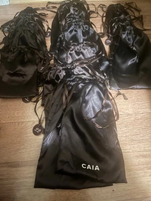 Tomma Caia satinpåsar (1-24) - Säljer Caias mörkbruna satinpåsar till att göra en egen julkalender  eller liknande, jättefina.  (Nummer 2 har en kortare sidenband vid sidan)  Obs bara satinpåsar, inget innehåll! 