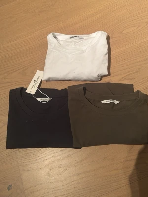 T-shirt i tre färger från John Henric - Tre stilrena t-shirts från John Henric i vitt, mörkblått och olivgrönt. Alla har rund hals och slimfit passform, perfekta för en clean och enkel look. Materialet är mjuk bomull som känns skönt mot huden. Snygga att matcha med jeans eller shorts. Kom privat vid minst fråga så löser vi det!😀