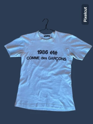 Comme des Garçons t-shirt CDG M - Säljer en vit t-shirt från Comme des Garçons med svart tryck '1986 été COMME des GARÇONS' på framsidan. Materialet är 100% bomull. Mått 📏 : längd 65 cm ✅ och bredd 50 cm ✅. Det står M men den passar som en lite större S. Modellen är 188cm lång och väger 68kg. 🧍‍♂️ Inget kvitto tyvärr så kan inte bevisa äkthet, däremot ser den helt legit ut!😇❤️Bara att skriva om du har några frågor! Priset är inte hugget i sten! 🪨 Jag skickar inom 1-2 dagar! 📦🚚