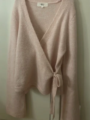 Ljusrosa omlottkofta från Gina Tricot - Mysig rosa omlottkofta från Gina Tricot med knyt i sidan och v-ringad hals. Koftan är mer rosa i verkligheten än på bilden . Pris kan diskuteras 
