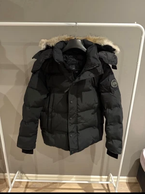 Svart canada goose Wyndham  - Tja! Säljer denna as feta svarta canada Goose Wyndham jackan i nyskick. Jackan är aldrig använd. Inget kvitto finns! Storlek @, han på bild är 185cm, 75kg. Hör av er vid funderingar!