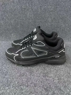 Svarta Dior sneakers med vita detaljer - Snygga svarta sneakers från Dior med vita kontrastdetaljer och logga på sidan. Skorna har en rund tå, platt sula och snörning. Materialet är en mix av mesh och syntet, vilket ger både komfort och stil. Perfekta för dig som gillar exklusiva streetwear-vibes.