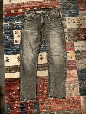 Levi's 502 grå jeans W30 L32 - Säljer ett par grå Levi's 502 jeans med klassisk femficksdesign och raka ben. Jeansen har en snygg tvättad look och är tillverkade i slitstarkt bomullsmaterial. Passformen är relaxed taper och de har normal midja. Perfekta till sneakers och hoodie.