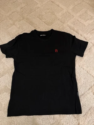 Svart Palm Angels t-shirt med röd logga - Palm Angels Tröja – Svart 👕 Storlek: M 🖤 Färg: Svart 🔄 Skick: 7/10 – tydligt använd, men hel och utan större defekter 💎 Märke: Palm Angels