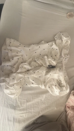 Söt vit bluss med polka dots  - Söt vit bluss med polka dots och en svart rosett fram till. Har en fläck men syns inte då den är på insidan.