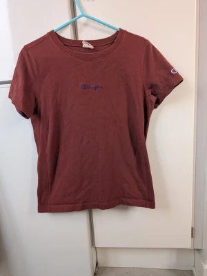 Vinröd Champion t-shirt i bomull - Säljer en vinröd t-shirt från Champion i mjuk bomull. Klassisk passform med korta ärmar och rund hals. Broderad Champion-logga på bröstet och ärmen. Rejäl lite tjockare t-shirt. 