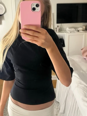 Svart omlottopp från Nelly - Säljer en svart omlottopp från Nelly i storlek XS. Toppen har halvlånga ärmar, tight passform och öppen rygg med breda knytband bak. Materialet är mjukt och stretchigt. Använd ett fåtal gånger 