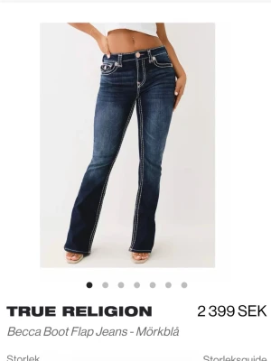 Mörkblå True Religion bootcut jeans - Säljer ett par mörkblå True Religion Becca Boot Flap jeans med kontrastsömmar och ikoniska fickdetaljer bak. Byxorna har bootcut passform som ger en snygg siluett. Klassisk jeanslook med slitningar och rejäla fickor fram och bak. Skriv privat för fler bilder. Finns små defekter. Originalpris 2400. Säljs inte längre på nätet.