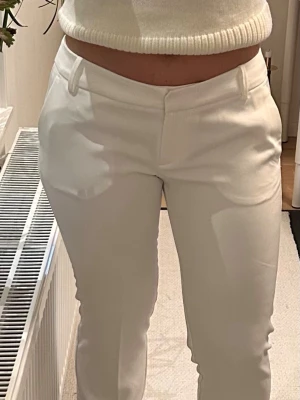 Nya via flare kostymbyxor PW Vera Bik Bok - Nya vita kostymbyxor med flare/bootcut passform och låg midja. Byxorna har klassiska fickor fram och bälteshällor. Materialet känns mjukt och har en lätt stretch, vilket gör dem riktigt bekväma. Perfekta till en snygg topp eller kavaj. Fräscha low waist byxor med flare i kritvit 👌🤩  Modell: PW Vera (storlek 40 men lägger den under 38 lite liten i storleken, har därför lagt den på M, 38)  Finns i butik, googla gärna om och läs om modellen. 