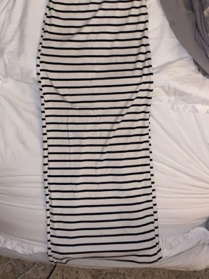 Randig långkjol med slits - Säljer en långkjol med svartvita horisontella ränder. Kjolen har en snygg slits bak som ger extra rörelsefrihet och en trendig look. Materialet känns mjukt och stretchigt. 