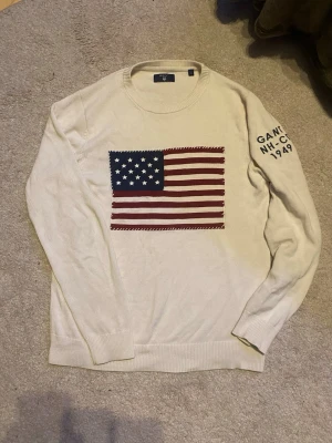 GANT knit / stickad tröja – S 🧶 - Snygg stickad tröja från GANT i off-white. USA-flagga framtill + text på ärmen. Perfekt till vardag eller lager-på-lager.  ▫️ Storlek: S ▫️ Skick: Bra ▫️ Färg: Off-white ▫️ Passform: Normal  I fint skick ✨ Skriv vid frågor!
