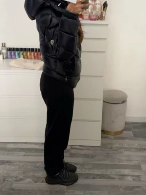   Moncler Maya äkta - Säljer en svart, glansig pufferjacka från Moncler med luva och dragkedja. Jackan har en quiltad design. Jackan har inga skador. Passform är normal 