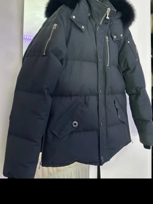 Svart Moose Knuckles dunjacka med päls - Säljer en svart dunjacka från Moose Knuckles med fluffig svart päls på huvan. Köpt från minto kvitto finns. Som ny!