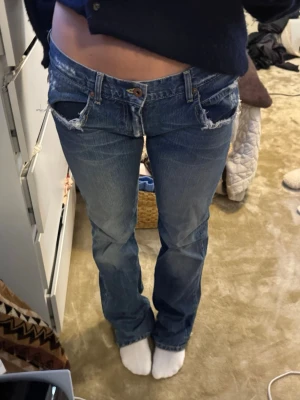 Lågmidjade blå bootcut jeans - Skriv vid frågor!❤️Säljer ett par blå lågmidjade jeans med bootcut-snitt. Jeansen har slitna detaljer vid fickor och benslut, klassisk femficksmodell och tydlig logga bak. Perfekta för dig som gillar en avslappnad och trendig look.