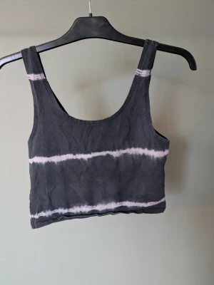 Svart och vit tie-dye linnetopp - Säljer en svart och vit tie-dye linnetopp från FB Sister i storlek M. Toppen är ärmlös med breda axelband och croppad passform. Tillverkad i mjuk bomull, perfekt för sommardagar eller som ett lager under en skjorta.