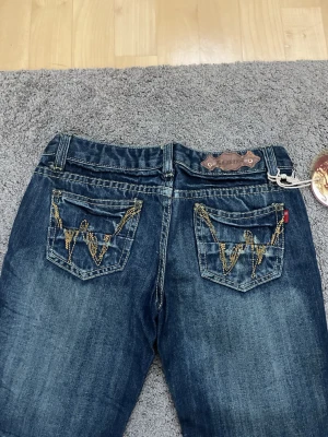 Y2k jeans med broderade bakfickor  - Säljer dessa lågmidjade bootcutjeans med snygga detaljer på fickorna. Lappar kvar, mått finns i bilderna. Super snygga o passar till allt! Skriv vid intresse❤️
