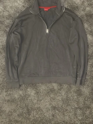 Mörkgrå half zip tröja från RYVLS - Mörkgrå långärmad tröja från RYVLS med halv dragkedja och hög krage. Tillverkad i mjuk bomull och polyesterblandning, perfekt för chill dagar. Klassisk och enkel design utan mönster, passar till det mesta.