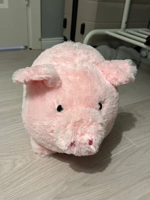 Rosa spargris gosedjur - Söt rosa spargris i form av ett mjukt gosedjur. Perfekt för att spara pengar på ett roligt sätt. Den har en öppning på ovansidan för att stoppa in mynt och en öppning med lock på undersidan för att ta ut dem.