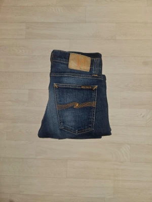 Nudie Jeans blå jeansbyxor - Hallö! Nu säljer vi ett par lite schyssta Nudie jeans i en tvärfet urtvättad blå färg. Modellen är slim och har en lite schysstare passform. Jeansen har inga defekter och är till dig som vill bli lite grischigare😉