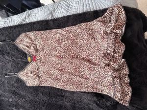 Leopardklänning Urban Outfitters M - Säljer en leopardmönstrad kortklänning från Urban Outfitters Archive i storlek M. Klänningen har tunna axelband, volangkant nertill och en liten röd rosett framtill. Materialet känns mjukt och följsamt, perfekt för dig som vill sticka ut.