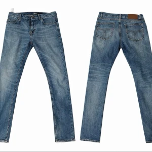 Tiger of sweden blå jeans slim fit - Säljer ett tos jeans i blå tvätt med snygga slitningar och kontrastsömmar. Modellen har en slimmad passform (pistolero), fem fickor och normal midja. Tillverkade i slitstarkt bomullsjeans med läderpatch bak i linningen. Storlek 29 32
