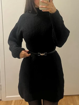 Svart kort stickad klänning  - Säljer en svart, ribbstickad klänning med lång ärm och figurnära passform. Använd väldigt få gånger.  Kommer inte med bältet!!