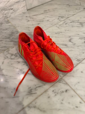 Röd/orangea adidas futsal skor - Säljer ett par riktigt snygga röda adidas futsal skor, nästan aldrig använda. Skriv för fler bilder, köpare står för frakt och pris kan diskuteras!