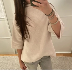 Rosa-Beige stickad trekvartsärm - Mysig rosa - beige stickad tröja med trekvartsärmar och avslappnad passform. Perfekt för lager-på-lager och enkel att matcha med jeans eller kjol. Stilren och enkel design som passar till många tillfällen.